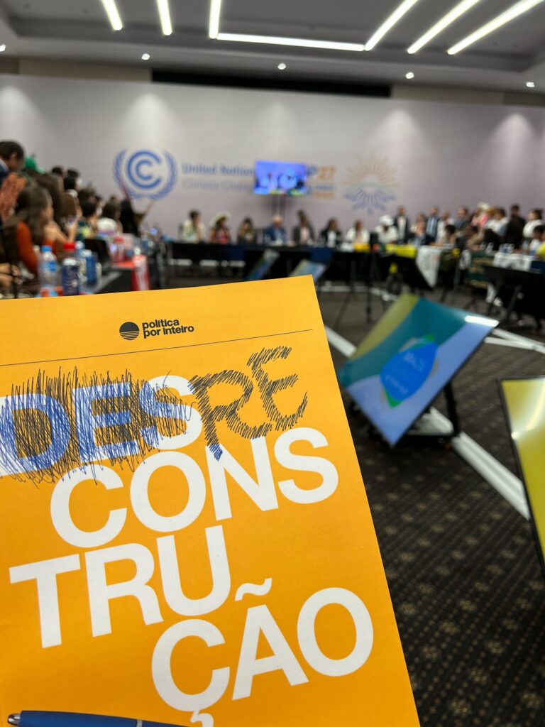Capa do documento Reconstrução em primeiro plano, com presidente eleito Lula e equipe ao fundo em reunião na COP 27